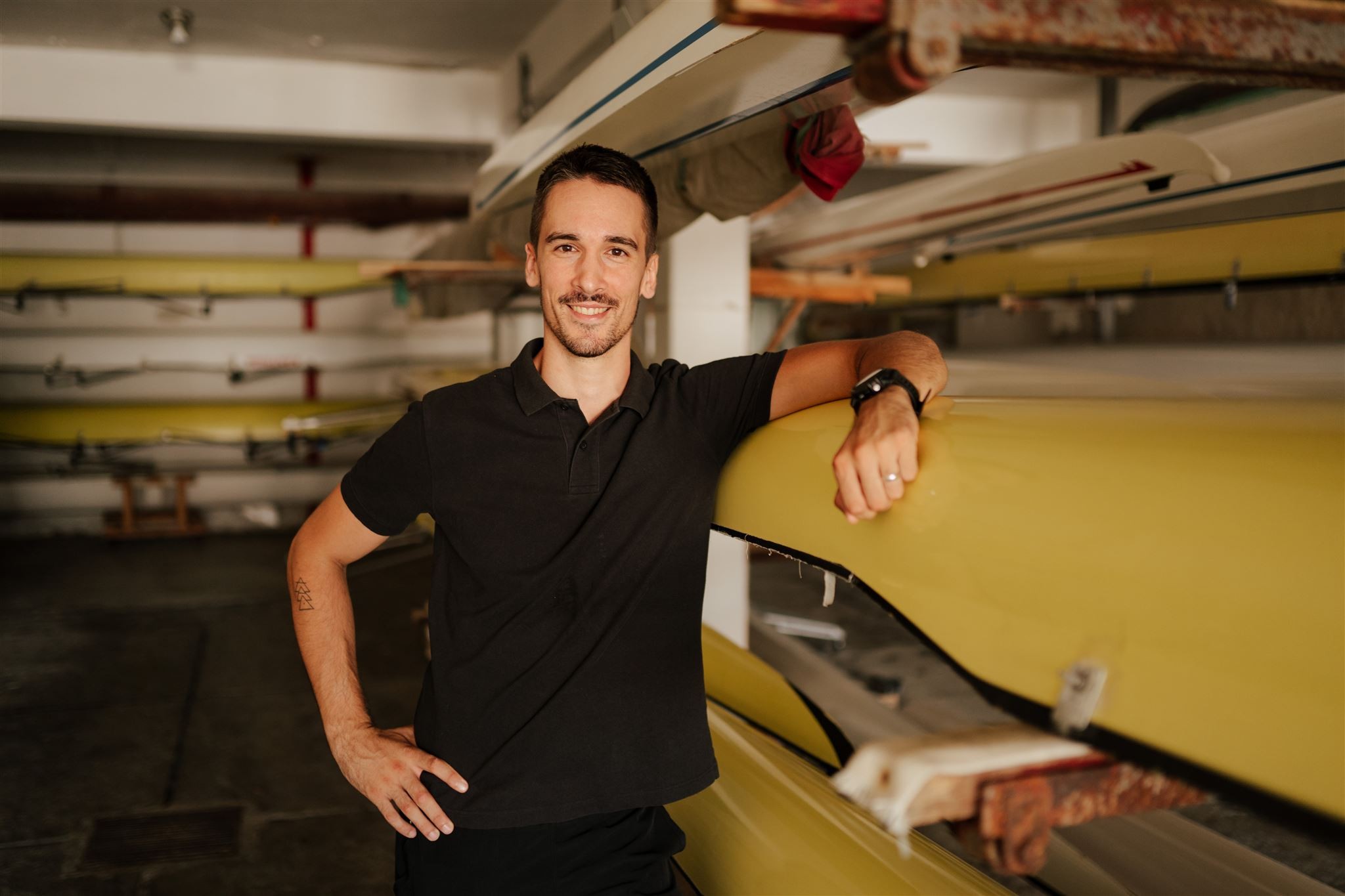 Karlo smiling, leaning on a boat in the boat house